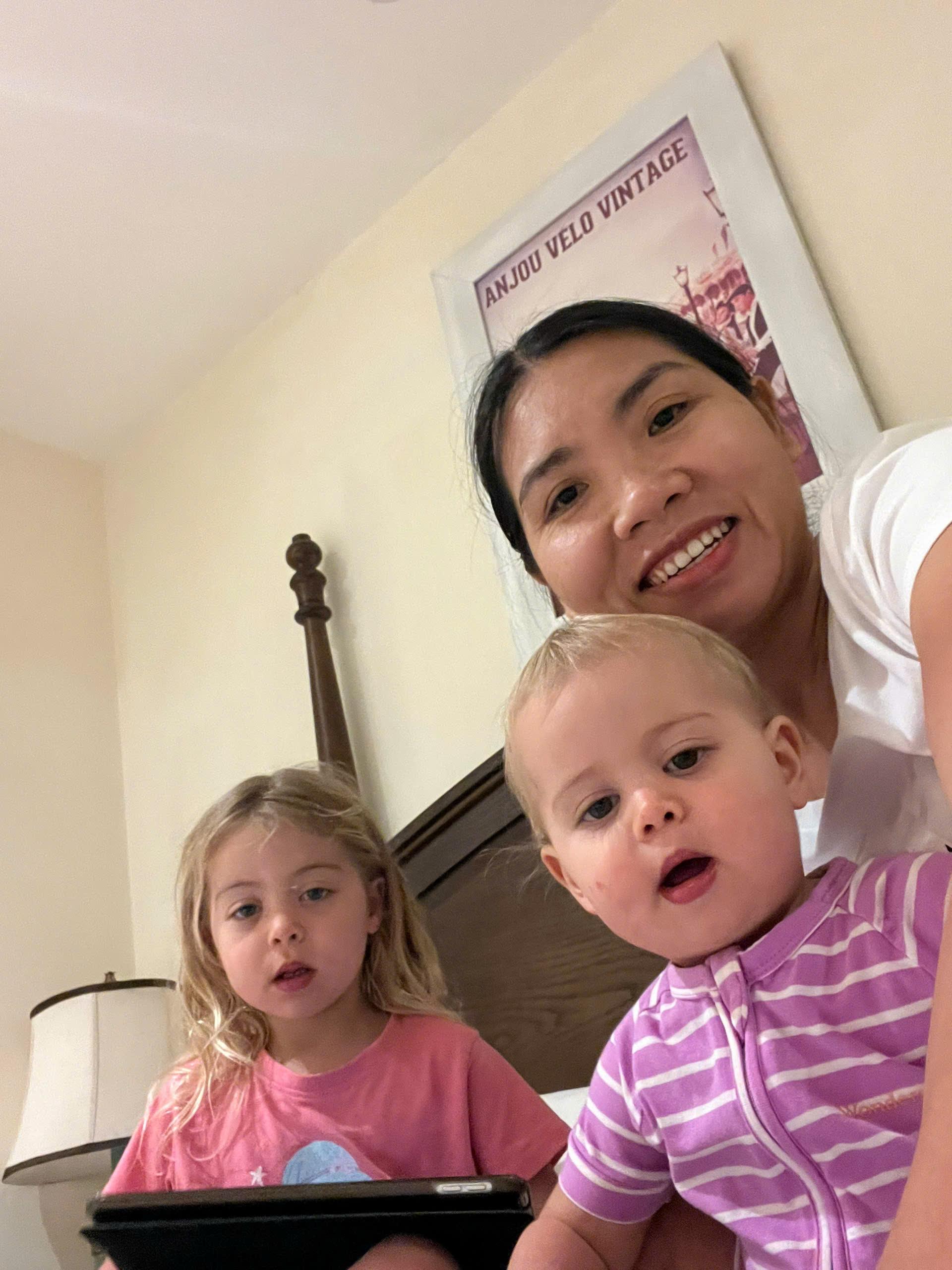 Professional babysitter Anh Nguyen playing with two children in a bedroom in Vietnam
