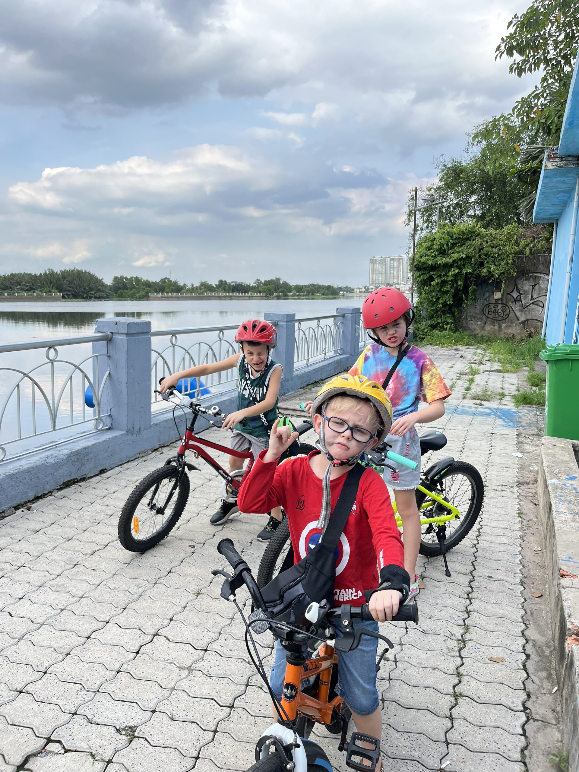 Happy family and children with English-speaking babysitter Anh Nguyen in Vietnam - Fun outdoor biking adventure by the lake