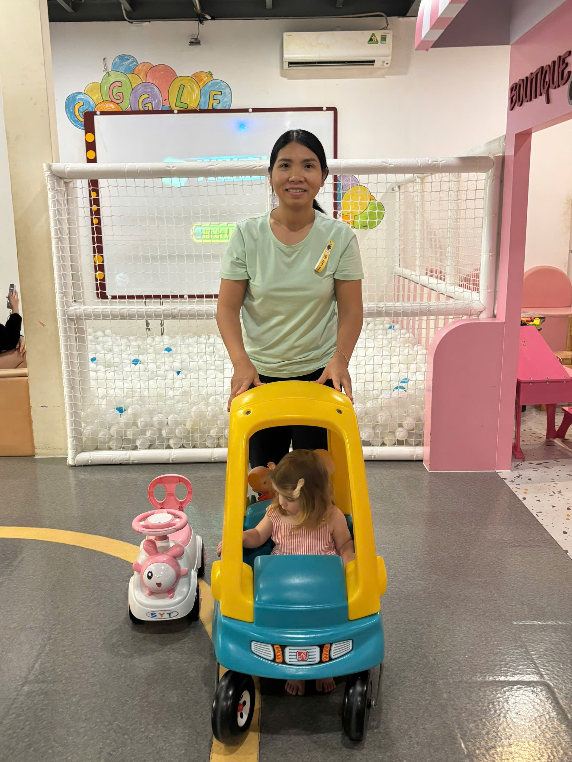 Happy family and children with English-speaking babysitter Anh Nguyen in Vietnam - Exploring indoor play area with a toddler girl
