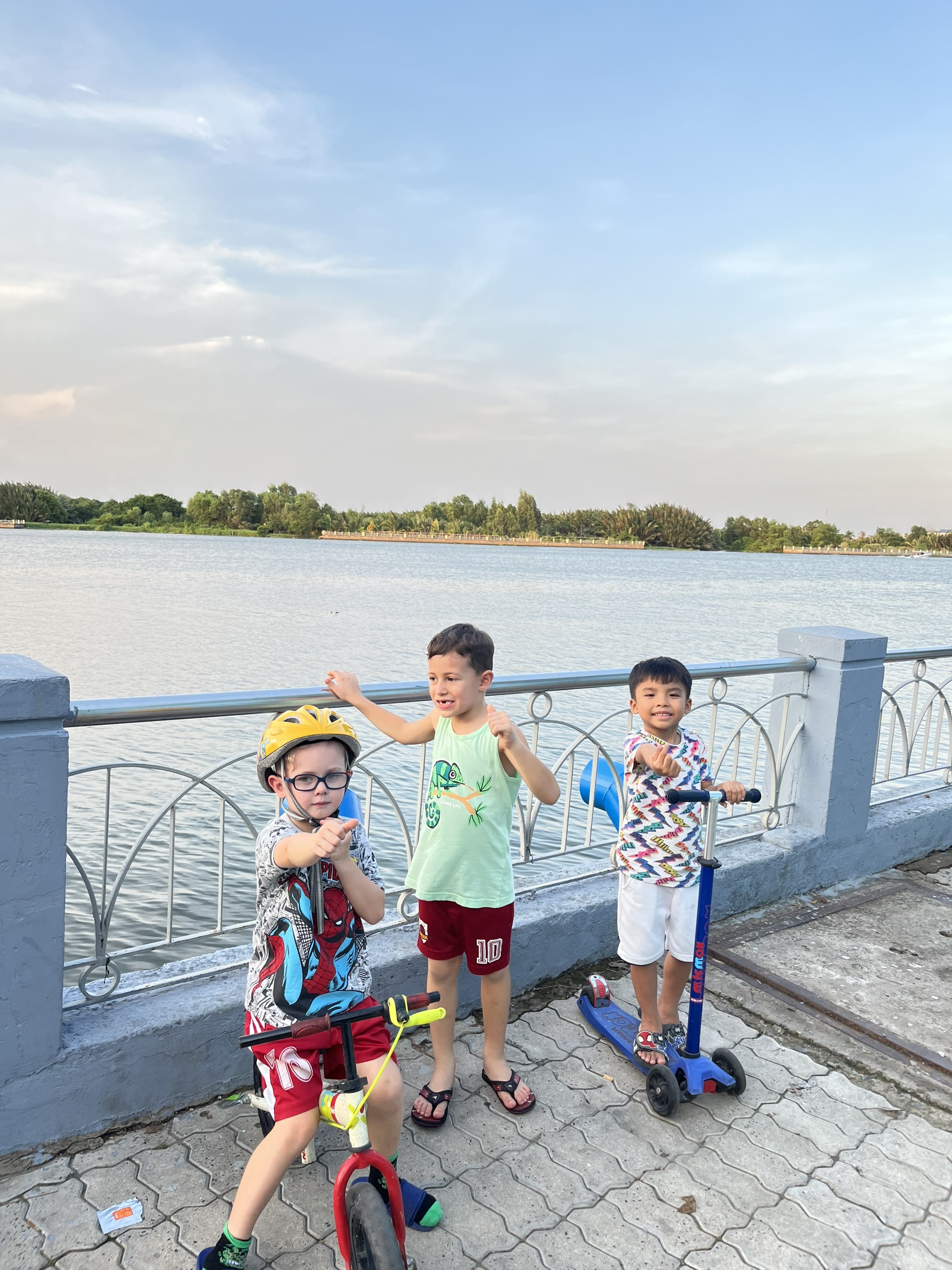 Happy family and children with English-speaking babysitter Anh Nguyen in Vietnam - Active boys with bikes and scooters during outdoor session